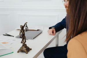 Cadre professionnel avec des avocats et une statue de Lady Justice discutant de documents juridiques.